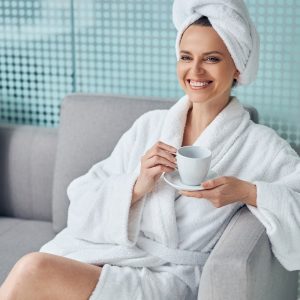 High-spirited young female with a cup of coffee and a saucer sitting on the couch
