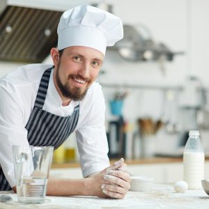 Chef of bakery-shop leaning at workplace