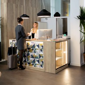 Shot of attractive female recepcionist giving room key card to client in hotel.