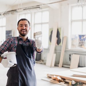 Happy young painter holding paint brush and showing it to camera.